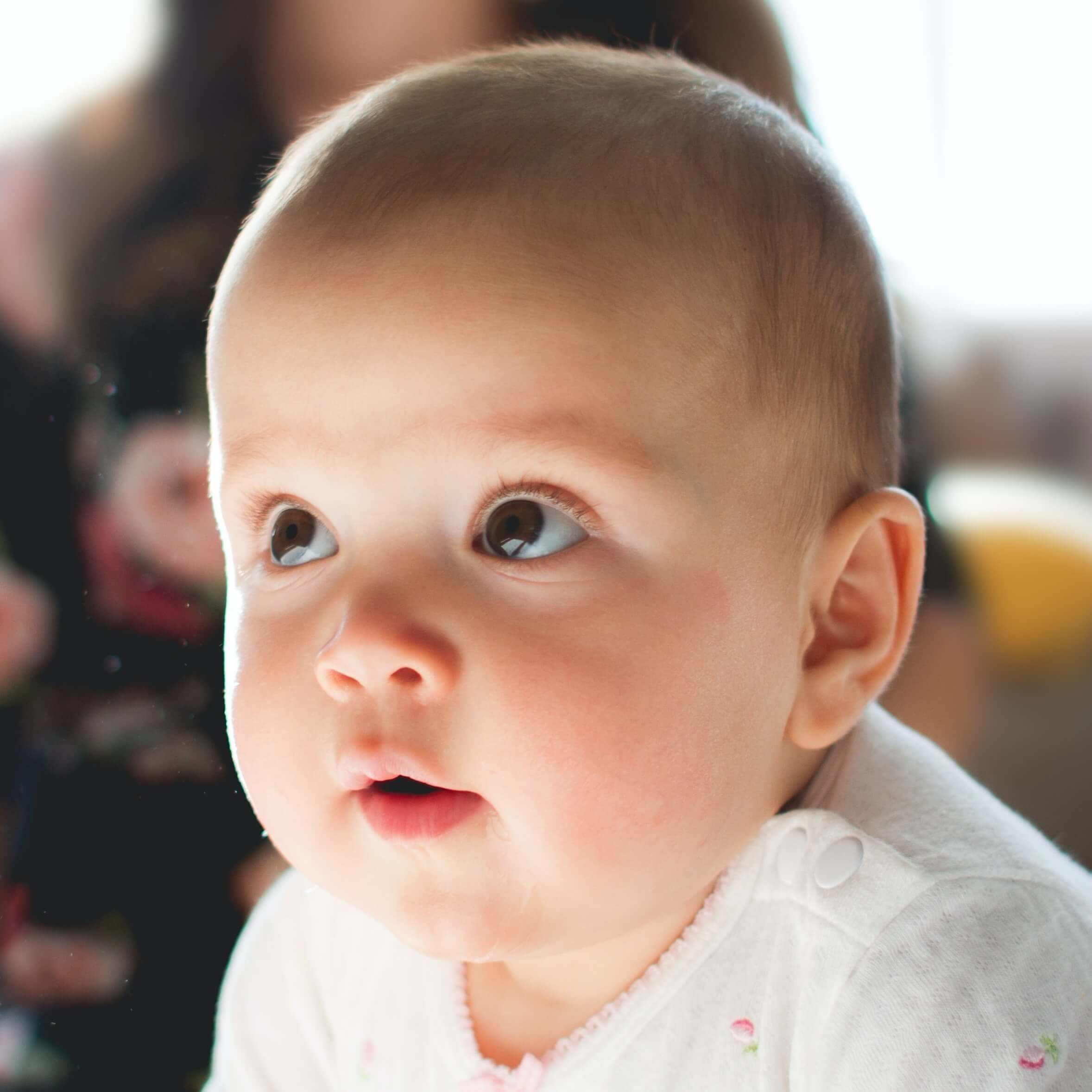 Tændt dåbslys med far og baby sløret i baggrunden.