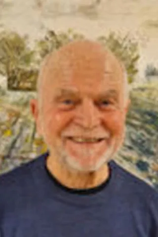 Portræt af en smilende skaldet mand med hvidt skæg og blå skjorte