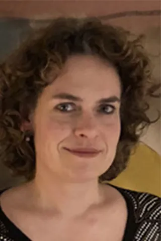 Portræt af en kvinde med krøllet brunt hår og mønstret top.